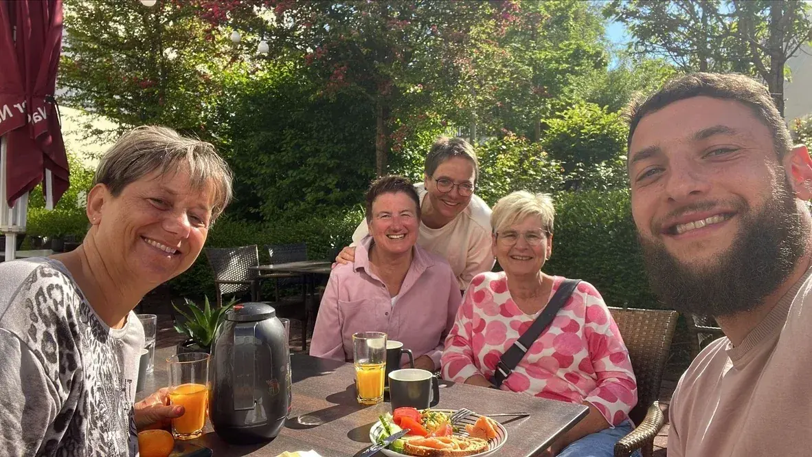 Gäste genießen gemeinsam eine Pause auf einer sonnigen Caféterrasse