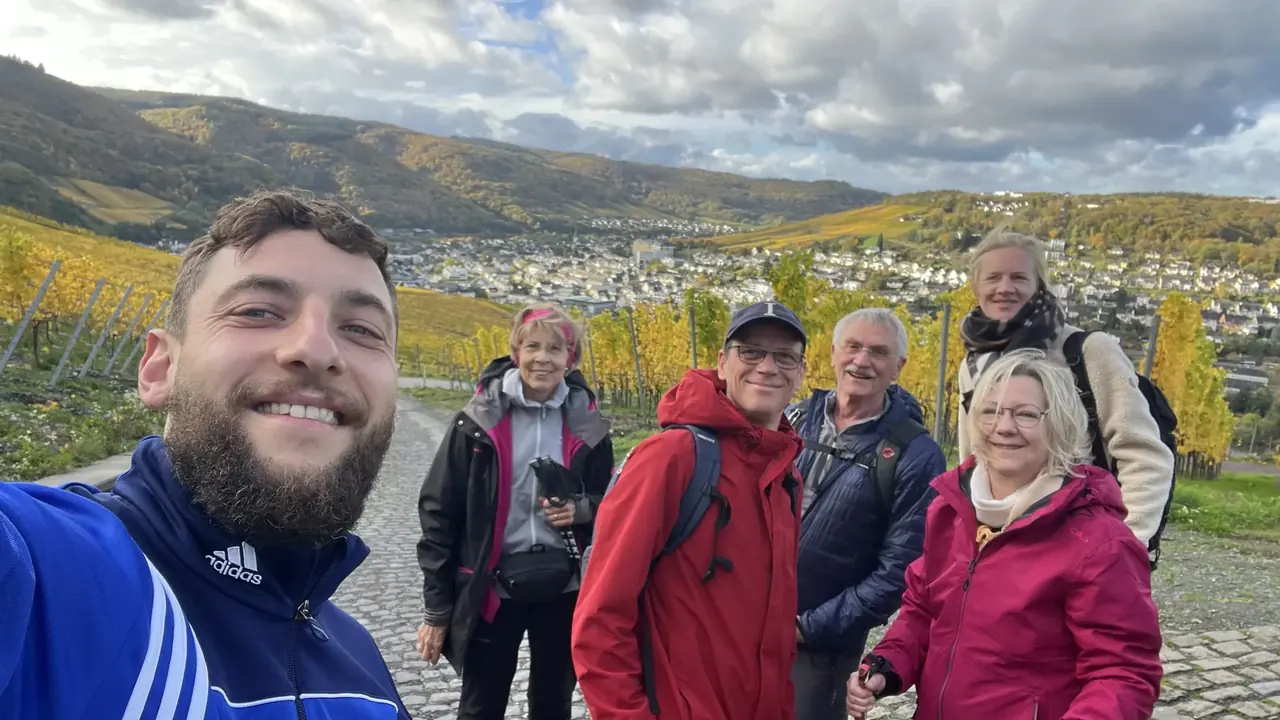 Trainer Wadim mit Gästegruppe beim Wandern in den herbstlichen Weinbergen