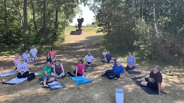 Gruppe beim Beweglichkeitstraining auf Matten unter Bäumen