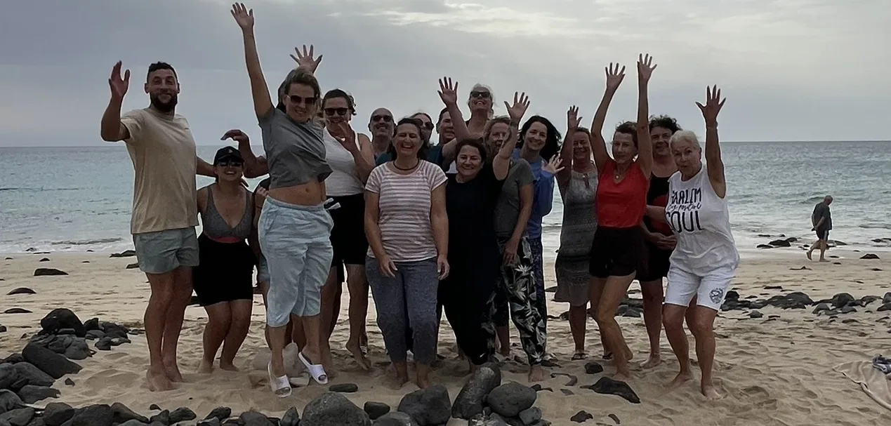 Gruppe mit erhobenen Armen am Strand
